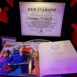 Certificate from the New Starship Foundation restoring the TNG bridge and the History of the Federation book. The certificate and book on the red metal shelves