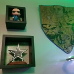 SHIELD and a Star A Funko of Agent Coulson, the Cowboys star and a booden shield with portraits of the Avengers burned into it hang on the East Wall