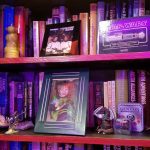 Books and knicknacks Several sci fi and fantasy books sir on the shelves behind photos of my son, CJ, ceramic dragons, a Yoda candle, lightsaber and Gen con dice.