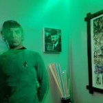 Spock and Wil Wheaton photo Lifesize cardboard cutout of Spock stands next to an autographed photo of Wil Wheaton in a red fez. At right is a partial view of a caricature painting print depicting every TOS episode.