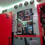 West wall with Star Trek autographed photos, plates, TV ornaments and the red painted door. The TV light string and some Trek ship ornaments hang from Christmas tree lights. West wall with Star Trek autographed photos, plates, TV ornaments and the red painted door. Bookshelves with various sci fi and fantasy books, family photos, and memorabilia in view.